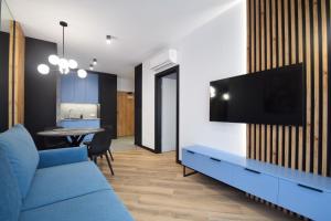 uma sala de estar com um sofá azul e uma televisão em Apartamenty LookAp Ustronie Morskie I przy plaży em Ustronie Morskie