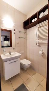 a white bathroom with a sink and a toilet at APARTAMENTY TR 11 Apartament nr 3 in Olsztyn +4 photos