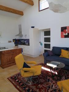 a living room with yellow chairs and a blue couch at Gîte Les Romarins in Saint-Jean-de-Minervois