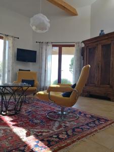 a living room with two yellow chairs and a table at Gîte Les Romarins in Saint-Jean-de-Minervois