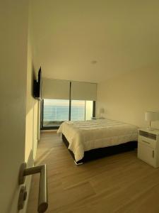 a bedroom with a large bed and a large window at Unica in Piriápolis