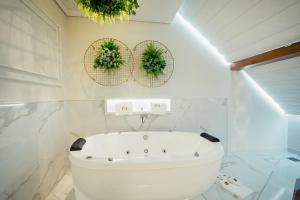 a white bathroom with a tub and two plants on the wall at Hotel e Restaurante GIRATÓRIO RF Vision - A melhor vista 360 de Gramado in Gramado +32 photos