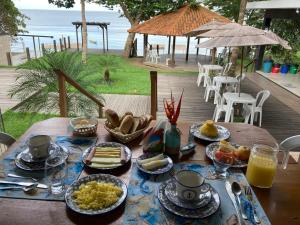 a wooden table with food on it with the ocean in the background at Chalés Casa de Vidro in Alter do Chao