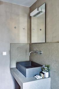 La salle de bains est pourvue d'un lavabo noir et d'un miroir. dans l'établissement Nikolaou residence, à Égine