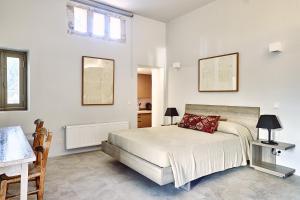 a white bedroom with a bed and a table and a window at Nikolaou residence in Aegina Town