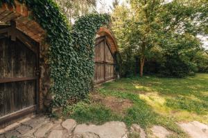 Farma Mračov في Kadov: مبنى مغطى من اللبلاب مع باب خشبي وساحة