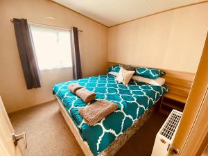 a bedroom with a bed with blue sheets and a window at The Hideaway in Cayton