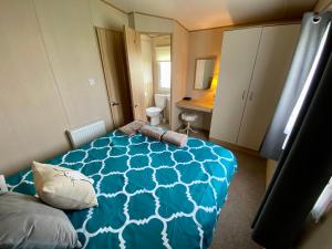 a bedroom with a bed with a blue comforter at The Hideaway in Cayton