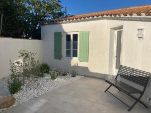 a bench in front of a house with a green shutter at Locations Ile de Ré in Sainte-Marie-de-Ré