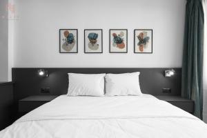 um quarto com uma cama branca com quatro fotografias na parede em New Era, Nilie Hospitality MGMT em Tessalônica