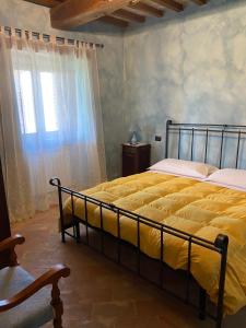 a bedroom with a bed with yellow sheets and a window at Caiferri Agriturismo in Gubbio
