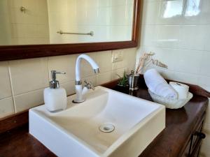 a white sink in a bathroom with a mirror at Casa 4 dorms 2 suites - localização perfeita no centrinho e rodeada de natureza in Alto Paraíso de Goiás