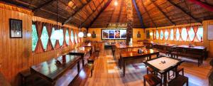 um restaurante com mesas e cadeiras de madeira e janelas em Banjara Camp and Retreat Sangla em Sāngla