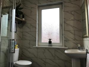 a bathroom with a toilet and a sink and a window at Bright Spacious 3-bed with office & patio, Preston in Preston