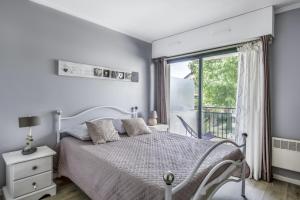 a white bedroom with a bed and a window at Charmant appartement lumineux pour 4 personnes au Pouliguen in Le Pouliguen