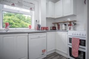 a white kitchen with white cabinets and a window at Harbour Court - 2 Bedroom Apartment - Saundersfoot in Saundersfoot