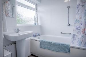 a white bathroom with a sink and a shower at Harbour Court - 2 Bedroom Apartment - Saundersfoot in Saundersfoot