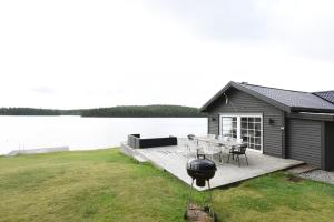 a house on a dock with a table and a grill at Cozy holiday home with its own jetty and panoramic views of Norra Orsjon in Arvika