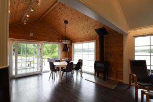 a dining room with a table and chairs and windows at Cozy holiday home with its own jetty and panoramic views of Norra Orsjon in Arvika
