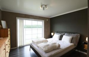um quarto com uma cama com almofadas brancas e uma janela em Cozy holiday home with its own jetty and panoramic views of Norra Orsjon em Arvika