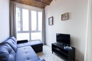 een woonkamer met een blauwe bank en een tv bij AB Sagrada Familia Bofill in Barcelona