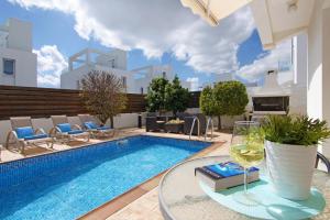 a swimming pool with a table and a glass of wine at Villa Nissinia in Ayia Napa