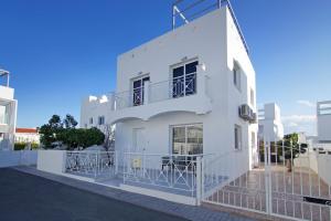 een wit gebouw met tafels op het balkon bij Villa Nissinia - Nissi Beach Area in Ayia Napa