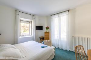 a white bedroom with a bed and a window at Hôtel De La Vallée in Dinard