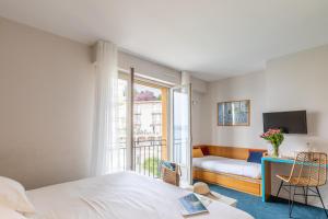 a bedroom with a bed and a desk and a window at Hôtel De La Vallée in Dinard