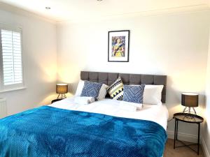 a bedroom with a large bed with a blue blanket at NEW! Luxury YELLOW HOUSE Bright Modern Detatched Home with PRIVATE PARKING, NETFLIX Close Luton, M1, and AIRPORT Ideal for Families, Professionals, Consultants, LONGER STAY OPTIONS in Caddington