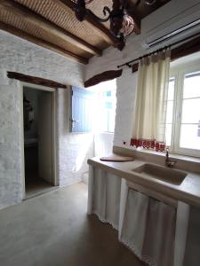 uma cozinha branca com um lavatório e uma janela em Traditional Suites in Chora Kythnos #1 em Kythnos