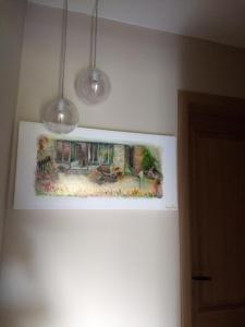 une peinture accrochée à un mur avec deux lumières dans l'établissement La grange aux dîmes, à Walcourt