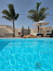 MrBrown - Cinzia Resort Beach في مازارا ديل فالو: وضع امرأة على جانب حمام السباحة