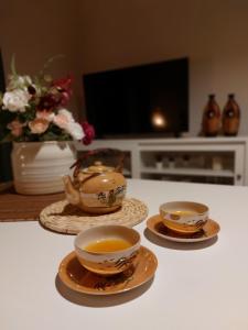Duas chávenas de chá e pratos numa mesa com uma televisão em Canopus em Petrití