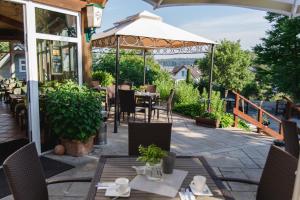 a patio with tables and chairs and an umbrella at Landhotel Peters - zwischen zwei Seen in Canow