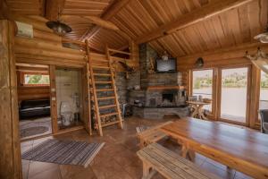 a log cabin living room with a wooden table and a fireplace at Marguse Metsamajad in Pärnu