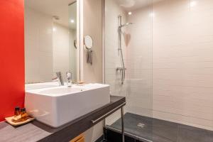 a white bathroom with a sink and a shower at Hôtel De La Vallée in Dinard