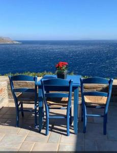 une table et des chaises bleues avec vue sur l'océan dans l'établissement ΠΕΤΡΙΝΟ στην Άνδρο, à Agia Eleousa