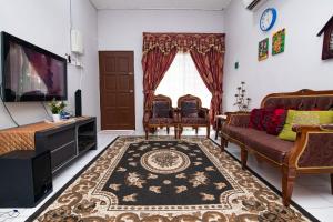 Tamu Nor Homestay Kuantan في كُوانتان: غرفة معيشة مع أريكة وتلفزيون
