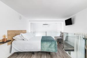 a white bedroom with a bed and a chair at Open Sea Suites in Las Palmas de Gran Canaria
