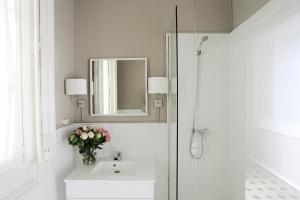 uma casa de banho branca com um lavatório e um espelho em Close to Passeig de Gracia em Barcelona
