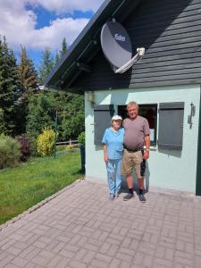 dos personas parados frente a una casa con un satélite en Ferienhaus Elke, en Kurort Altenberg