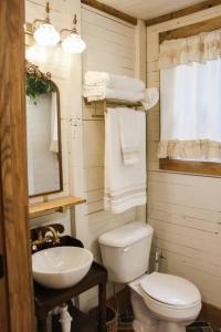 a bathroom with a white toilet and a sink at The Greenhouse Cozy Cottage- Walk to Downtown! in Opelika