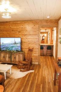 uma sala de estar com uma televisão numa parede de madeira em The Greenhouse Cozy Cottage- Walk to Downtown! em Opelika