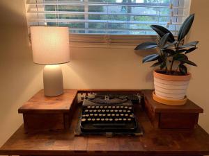 een bureau met een lamp en een oude typemachine en een plant bij The Greenhouse Cozy Cottage- Walk to Downtown! in Opelika