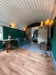 Gleis 1, Eisenbahn Waggon mit Whirlpool und Ofen في Dahlem: غرفة معيشة مع أريكة وطاولة