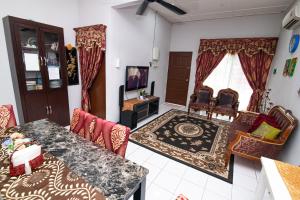 Tamu Nor Homestay Kuantan في كُوانتان: غرفة معيشة مع طاولة وكراسي وتلفزيون