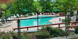 a fence around a swimming pool with chairs and umbrellas at Trailside Vacation Home 40 in Bella Vista