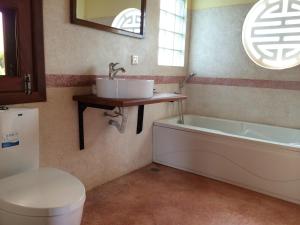 a bathroom with a sink and a tub and a toilet at Green Plateau Lodge in Banlung