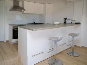 a kitchen with white cabinets and a counter with stools at APARTMANI SMILJA in Primošten